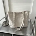 Minimalist beige canvas tote bag with fashion tag on industrial steel shelf - White