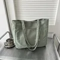 Minimalist light green tote bag with front pocket and white fashion label on a silver rack - Green