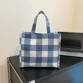 Borsa tote in tela a quadretti blu e bianchi con doppi manici su tavolo di legno - Blu