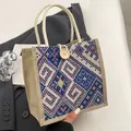 Detail of woven tote bag featuring geometric patterns, rope handles and a wooden button closure - Button Decor Style / Blue