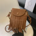 Brown faux suede crossbody bag with long tassels and woven strap in a modern studio setting - Brown