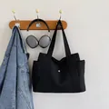 Minimalist black canvas tote bag in high-density fabric with metal snap button and side pockets - Black