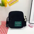 Compact black corduroy crossbody bag with green woven label and adjustable strap - Black