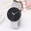 Minimalist quartz watch with black round dial and grey leather strap next to accessories - Gray