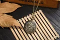 Dettaglio di un orologio da taschino vintage in bronzo con decori floreali su legno - Stile Loto Traforato