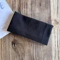 Dettaglio della fascia in maglia nera con trama verticale su una superficie in legno - Nero