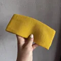 Gros plan du bandeau en tricot côtelé jaune gingembre montrant la texture et l'élasticité - Jaune