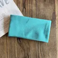 Detailed close-up of a turquoise knitted headband on a rustic wooden surface with a magazine - Lake Blue