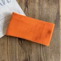 Dettaglio di una fascia sportiva arancione in maglia elastica su un piano di legno - Arancione