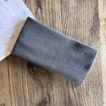 Dettaglio macro della fascia in maglia larga grigio scuro con trama morbida su legno - grigio scuro