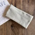 Detail of oat-colored ribbed knit headband folded on a natural wooden background - Grayish White