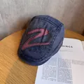 Nahaufnahme einer blauen Vintage-Jeansmütze mit roter Z-Stickerei auf einem Holztisch - M (55-59cm) / Marineblau