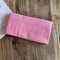 Pink knitted elastic headband for sports and daily wear on a vintage wood background - Pink