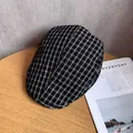 Detail of classic black and white plaid beret hat on a wooden desk with a magazine - M / Black
