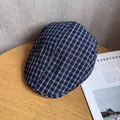 Detailed view of blue and white checkered ivy cap on a wooden table with soft lighting - M / Navy Blue