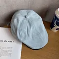 Close-up of light blue denim flat cap with twill texture on a wooden table surface - M / Light Blue