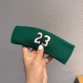 Detail of dark green knitted sports headband featuring embroidered number 23 logo - Green