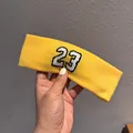 Primo piano di una fascia sportiva gialla con ricamo 23 e trama di tessuto a maglia - Giallo