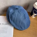 Detailed close-up of dark blue denim beret cap on light wooden texture with soft lighting - M / Dark Blue
