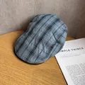 Detailopname van de blauw-zwarte geruite stof van de platte pet op een houten tafel - M / Blauw en Zwart Geruit
