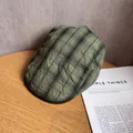 Detailopname van olijfgroene geruite baret op houten tafel met tijdschrift decoratie - M / Olijfgroen Ruit
