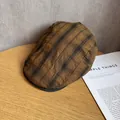Detailed view of vintage plaid newsboy cap with black brim on a wooden surface - M / Brown & Black Plaid