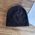 Vista piatta di un berretto nero in maglia su legno scuro con una rivista vintage - M / Nero