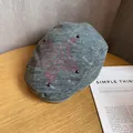 Detailed texture of denim newsboy cap featuring red embroidery and metal rivets on wood - Medium / Gray