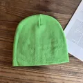 Berretto in maglia verde brillante su scrivania in legno accanto a un libro - M / Verde Fluorescente