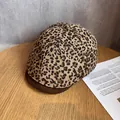 Détail d'une casquette plate léopard avec visière marron posée sur une table en bois naturel - Réglable / Kaki