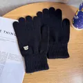 Detail of black knitted gloves with cute white bear patch and ribbed cuff on wooden surface - One Size / Black