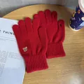 Close-up of red knit gloves with bear embroidery and functional touchscreen fingertip design - One Size / Red
