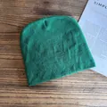 Berretto in maglia verde su superficie in legno vintage con sfondo di una rivista - M / Verde