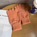 Close-up of orange knit gloves with cute bear embroidery on a rustic wooden table - One Size / Orange