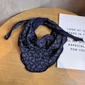 Close-up of navy blue floral triangle scarf with delicate white lace trim on wood surface - Navy Blue