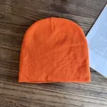 Tessuto a maglia dettagliato di un berretto arancione vivace su fondo in legno - M / Arancione