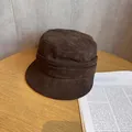 Detail of dark brown faux suede newsboy hat with layered pleats on a wooden table - M (55-59cm) / Coffee