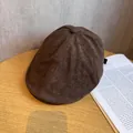 Detalle de gorra newsboy de ante marrón oscuro con hebilla metálica sobre madera - Ajustable (55-59cm) / café