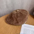 Detalle de gorra newsboy de pana marrón sobre mesa de madera con libros decorativos - Mediano / Camel