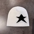 Close-up of white knitted beanie featuring a large black star pattern on a gray surface - M / White With Black Star