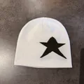 Detailed shot of a white knit beanie with black star pattern on a textured background - M / White With Army Green Star