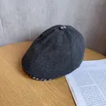 Detail of a dark gray wool newsboy cap with a black and white checkered under-brim - M (55-59cm) / Gray