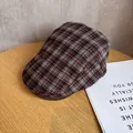 Detailansicht der rot-schwarzen Karo-Schiebermütze auf einem Holztisch mit sanftem Licht - M(56-58cm) / Weinrotes Karo