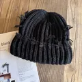 Detalle del gorro de punto negro con flecos sobre una mesa de madera con una revista - M / Negro