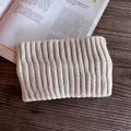 Close-up of beige ribbed knit headband texture on a dark wood table with a magazine - Beige