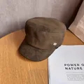 Detail eines dunkelbraunen Wildleder-Reiterhutes mit goldener Riod-Plakette auf Holztisch - M (55-58cm) / Khaki