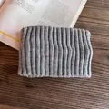 Detail of grey knitted headband showing vertical ribbed texture on a wooden desk - Gray