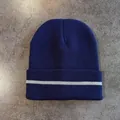 Detail of navy knit beanie with rolled cuff and reflective silver stripe on stone surface - M (52-58cm) / Navy Blue