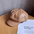 Detailed view of khaki faux leather newsboy cap with stitching and top button on wood - M (55-59cm) / Camel