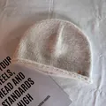 Detail of soft cream knit beanie with fluffy texture and oval silver metal brand tag - M (55-59cm) / Beige